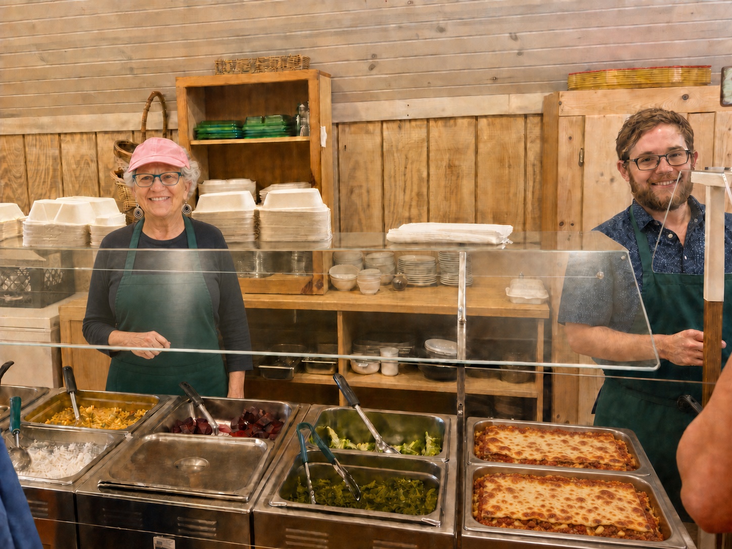 Chef Dolores and a team member behind the hot buffet line with fresh lasagna